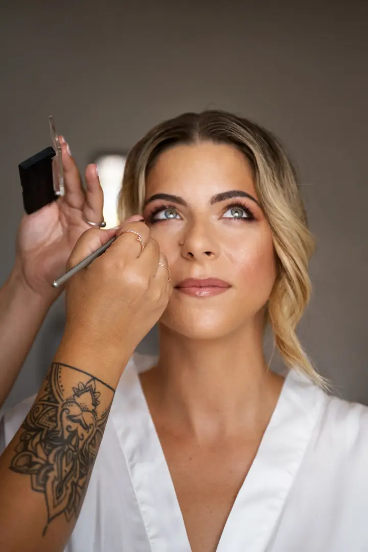 Makeup artist working on a bride's eye makeup with a fine brush